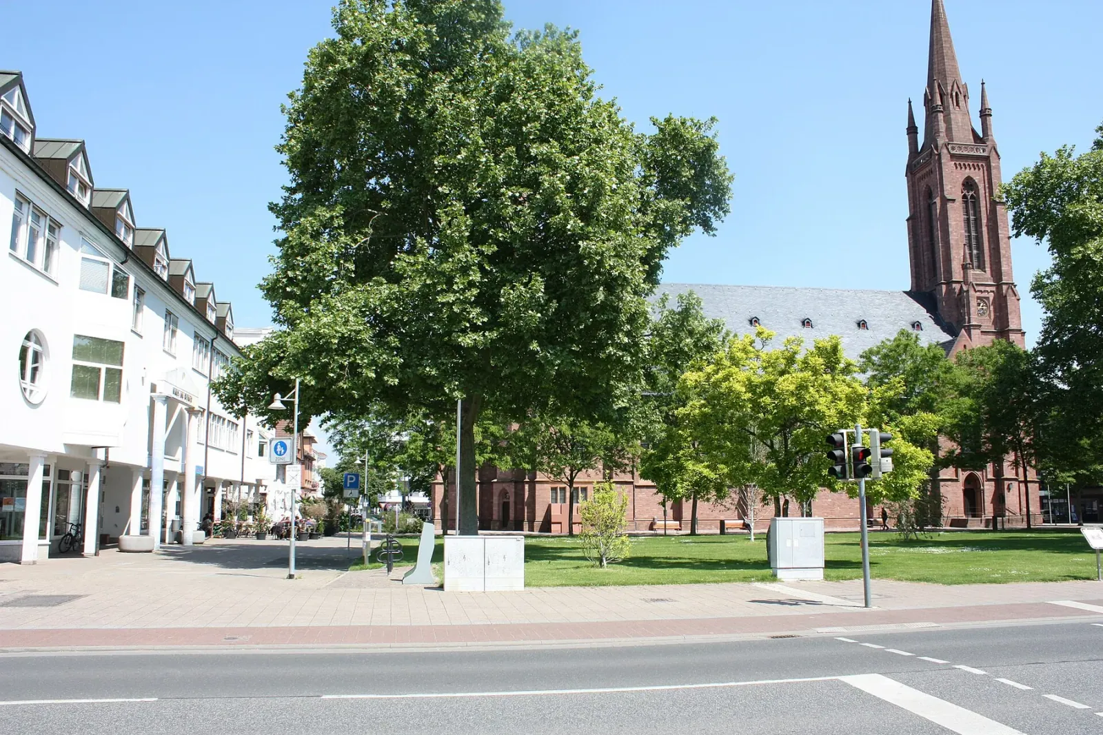 Sommertag in Lampertheim: Platz mit großer Platane, dahinter die Kirche aus rotem Sandstein