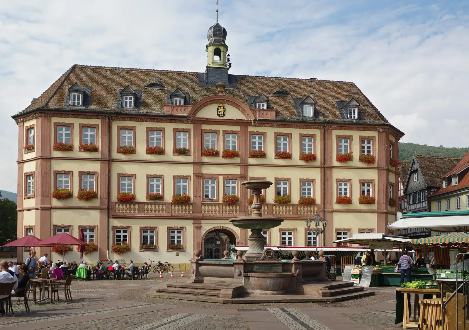 Der Marktplatz von Neustadt an der Weinstraße mit Rathaus, Brunnen und Marktständen an einem Sommertag